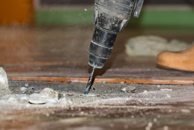 Concrete repair being done by a worker with a power drill